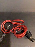 Coiled red PVC-coated steel cable lock with black keyed lock housing