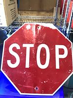 Full view of red aluminum STOP sign showing wear and mounting holes