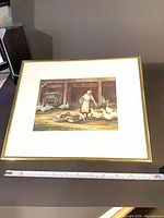 Full view of framed print showing barnyard scene and measuring tape for scale