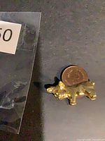 Top view of small gold brass bulldog figurine with coin for scale