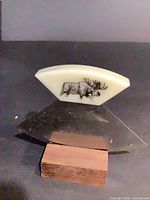 Ulu knife on wood stand, showing handle with moose design
