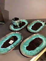 Set of three oval platters, mug on underplate, showing turquoise drip glaze