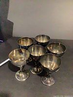 Six silver-plated cordial goblets grouped together showing form and tarnish