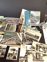 Overview of assorted vintage postcards spread on table showing Daytona 500 racing scenes, Eiffel Tower, Arc de Triomphe, scenic landscapes