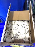 Open box showing loose white tealight candles in foil cups