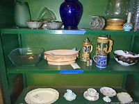 Shelf showing glass bowl, casserole dish, three of the steins, music box and candy dish