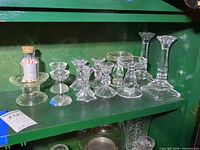 Group view of all candlesticks and matchstick jar on shelf