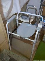 Front view of primary commode showing frame, gray seat and lid