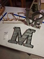 Group shot showing galvanized M, gold LOVE on wood base, silver LOVE sculpture