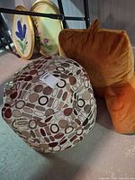 Patterned pouf cushion and orange backrest pillow together