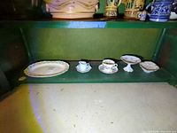 Entire lot on shelf: platter, pitcher, teacup with saucer, pedestal dish