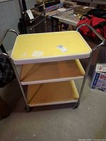 Full view of three-shelf metal cart on casters