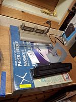 Boxed X-Acto paper trimmer with two hole punches displayed on top