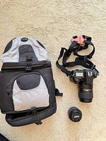 Camera backpack, DSLR with 18-300 mm lens attached, loose 35 mm lens and strap visible