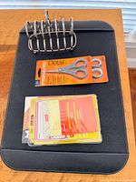 All items laid on desk pad: metal file organizer, two Fiskars scissors, Staples labels, OfficeMax index cards
