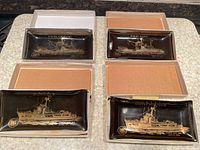 All four ashtrays in boxes showing ship names and artwork