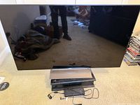 Front view of Sony 55" TV on stand with power cord visible