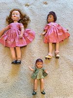 Three dolls on carpet showing overall condition and attire