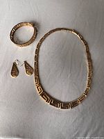 Full view of necklace, bangle, and earrings on surface