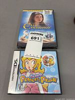 Front view of sealed Ella Enchanted DVD and sealed Super Princess Peach Nintendo DS game