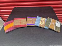 Five sealed zodiac coin and stamp sets arrayed on table