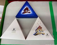 Three triangular Swarovski ornament boxes: blue early edition, two white with gold design (one marked 1997)