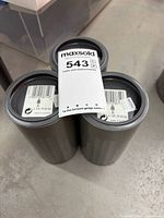 Three closed grey cylindrical Swarovski containers with lot tag visible