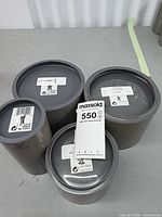 Four grey cylindrical Swarovski Silver Crystal boxes with lot tag visible