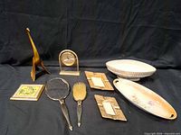 Group shot showing all ten items: brass figurine, tabletop mirror, two frames, wooden bird box, three vanity pieces, two ceramic dishes