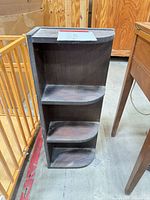 Front view of dark wood corner shelf with three tiers