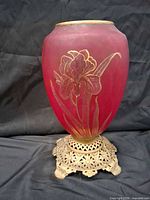 Full view of cranberry glass vase on ornate metal stand