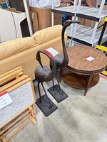 Two metal crane sculptures beside furniture showing full view