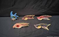 Five painted wooden fish on black backdrop