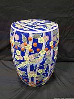 Full view of the ceramic pedestal showing blue glaze, floral and bird design, raised orange studs