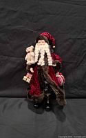 Front view of Santa figure showing velvet coat, fur trim, teddy bear, gifts