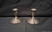 Front view of both silver-plated candle holders showing design and tarnish