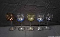 Front view of five tinted etched wine glasses