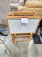 Front view of stacked folding tray tables on stand