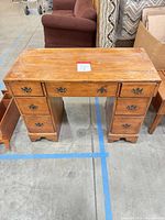 Front view of wooden desk showing drawers and hardware