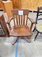 Front view of wooden swivel chair showing overall design and condition