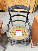 Full view of black wooden chair with cane seat