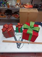 Three glitter gift boxes showing size comparison next to yardstick and wiring