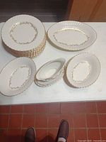 Entire dish set showing stack of 12 dinner plates, serving platter, two vegetable bowls and gravy boat