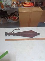 Full view of wooden war club next to ruler for scale