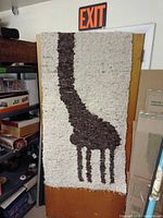 Full view of cream shag rug with brown giraffe silhouette hanging vertically