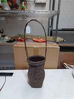 Front view of tall woven bamboo basket showing shape and handle