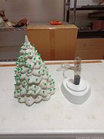 Ceramic tree beside separate light base with bulb and cord
