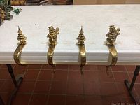 Front view of four brass stocking holders lined on table