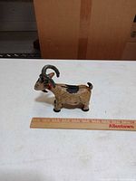 Left side view of cast iron Billy Goat bank with ruler for scale