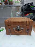Front view of closed leather-covered trunk showing latch, handle, straps.